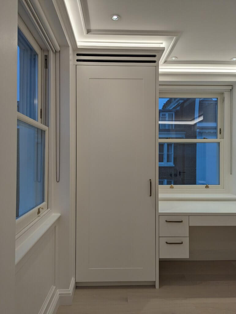 Joinery slots in dressing room cabinetry of the master suite for luxury air conditioning in a Kensington townhouse