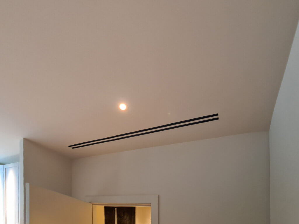 Plaster-in twin slot diffuser in residential bedroom for discreet air conditioning